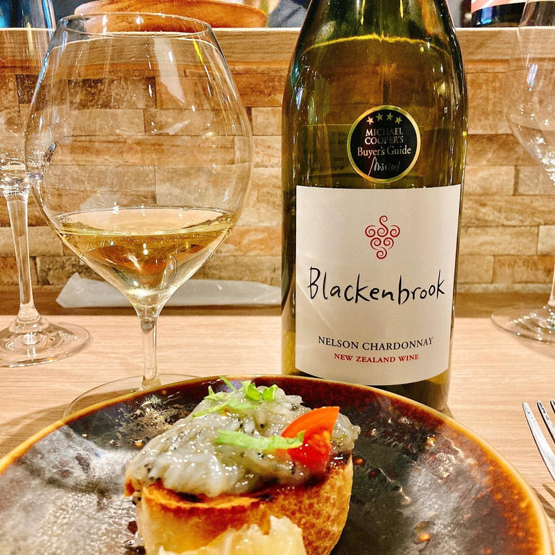 A delicious-looking dish of white bait sushi in the foreground with a bottle of Blackenbrook Chardonnay and a half-full wine glass in the background. 