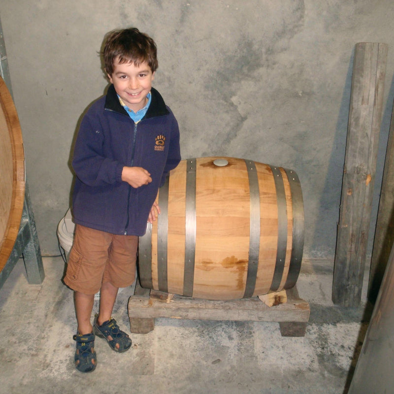 6-year old Thomas proudly stands next to the 120L Acacia barrel containing the Blackenbrook Thomas's Treasure Dessert Riesling.  He's smiling shily.  In the background you can see the concrete wall of the barrel hall at the Blackenbrook Winery.