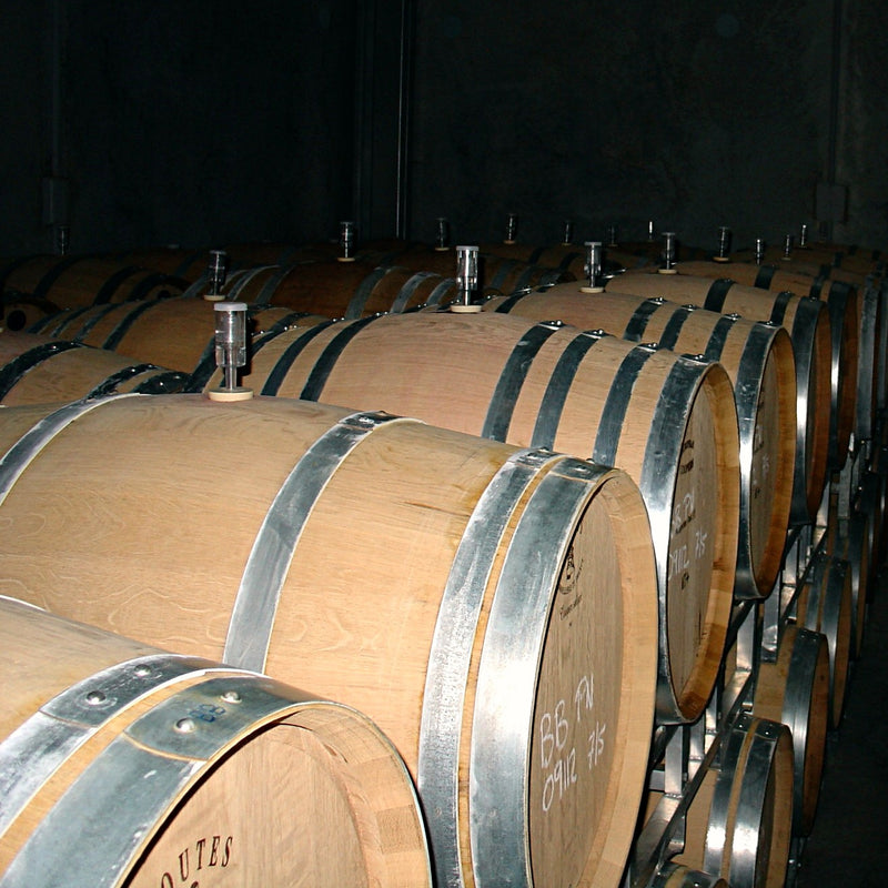 A row of new-looking oak barrels at the Blackenbrook Winery.  They have shiny metal hoops.  In the background another row of barrels can be seen. 