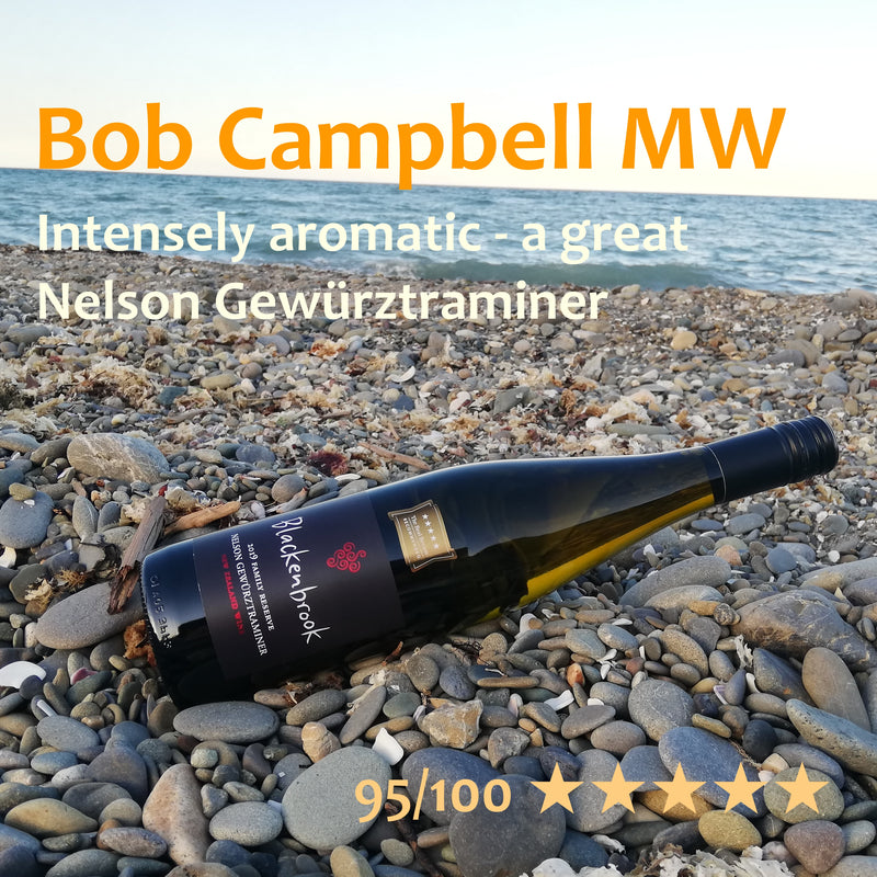A bottle of Family Reserve Gewurztraminer 2019 displayed on a pebbly beach in the soft evening light.  In the background you can see the sea and the evening colours of the sky.  